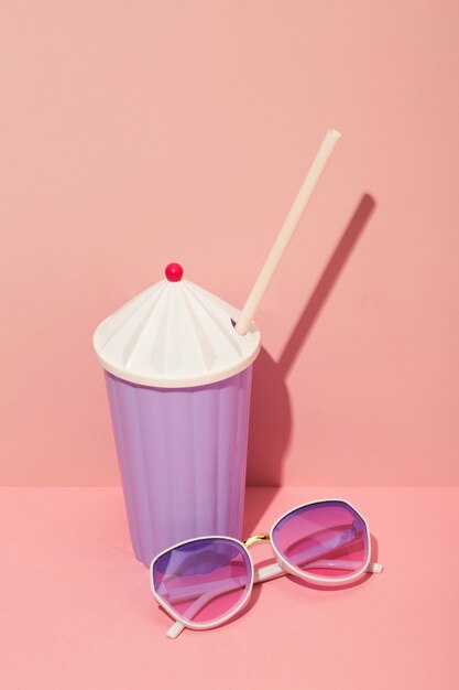 View of summer sunglasses with drink and straw