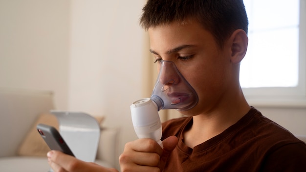 Foto gratuita vista dell'adolescente che utilizza il nebulizzatore a casa per problemi di salute respiratoria