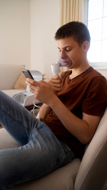 Foto gratuita vista dell'adolescente che utilizza il nebulizzatore a casa per problemi di salute respiratoria