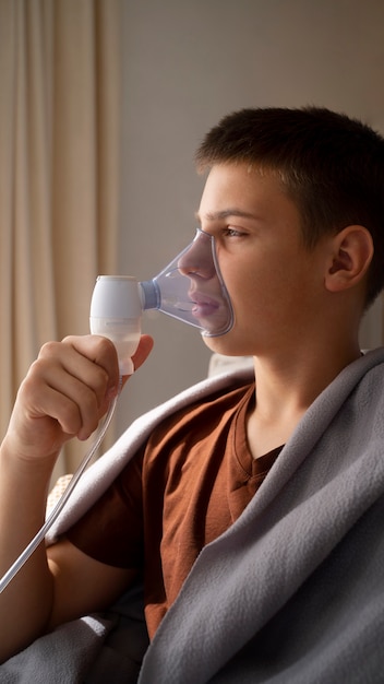 호흡기 건강 문제로 집에서 분무기를 사용하는 10대 소년의 모습