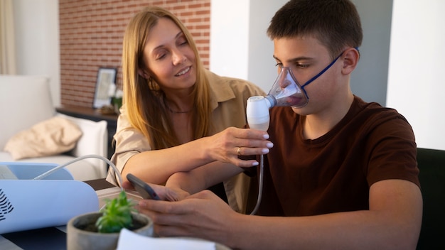 Foto gratuita vista dell'adolescente che utilizza il nebulizzatore a casa per problemi di salute respiratoria