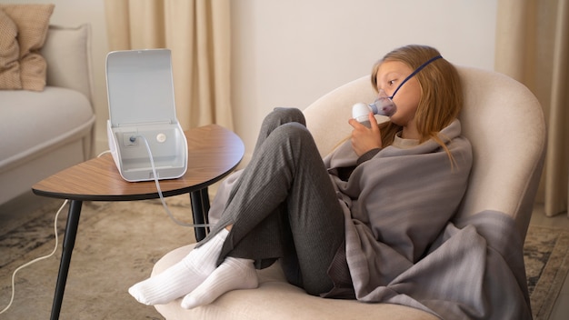 Foto gratuita vista dell'adolescente che utilizza il nebulizzatore a casa per problemi di salute respiratoria