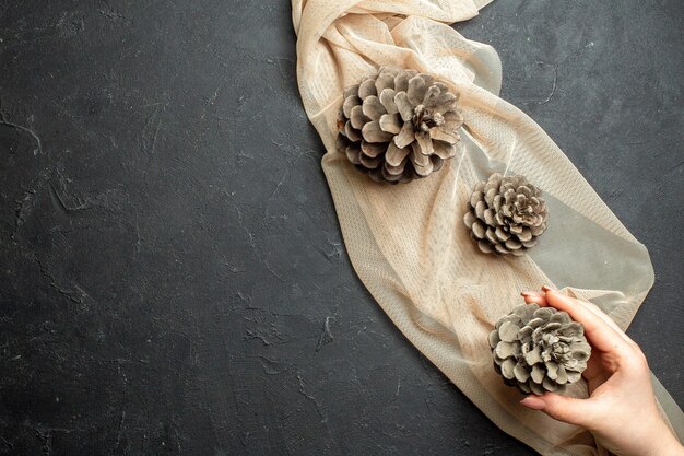 Above view of three conifer cones on nude color towel on black color background