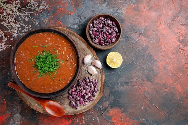 Sopra la vista dell'aglio dei fagioli della zuppa di pomodoro sul tagliere di legno e del cucchiaio sulla tabella dei colori della miscela