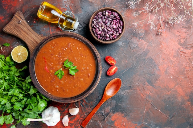 混合色のテーブルの茶色のまな板の上のトマトスープのビューの上