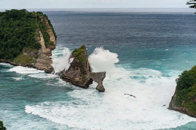 Вид на тропический пляж, морские скалы и бирюзовый океан, голубое небо. Пляж Ату, остров Нуса Пенида, Индонезия. Концепция путешествия. Индонезия