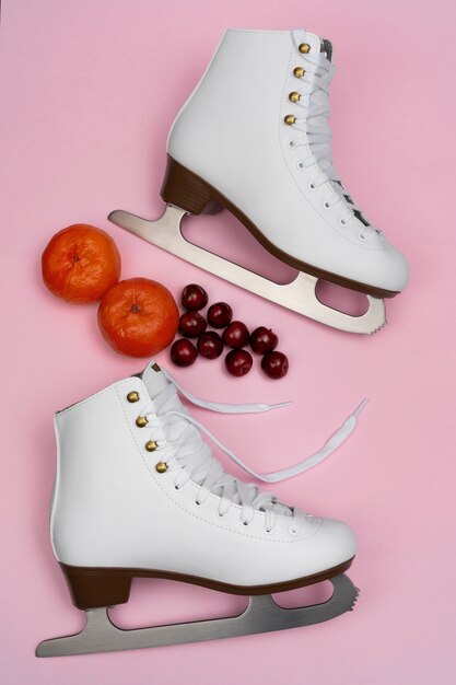 View of white ice skates with cherries and tangerines