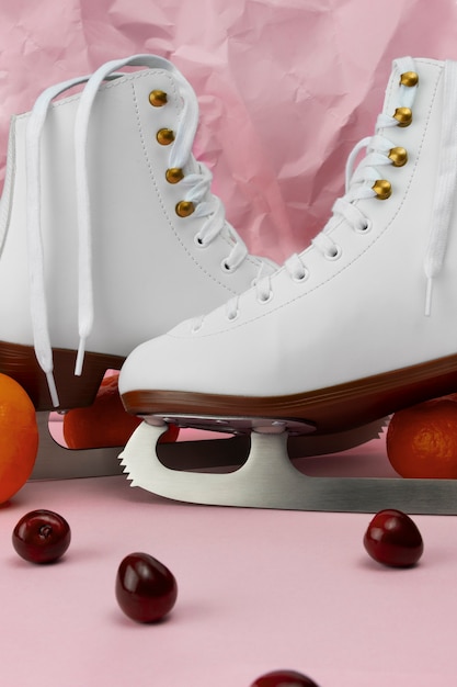 Free photo view of white ice skates with cherries and tangerines