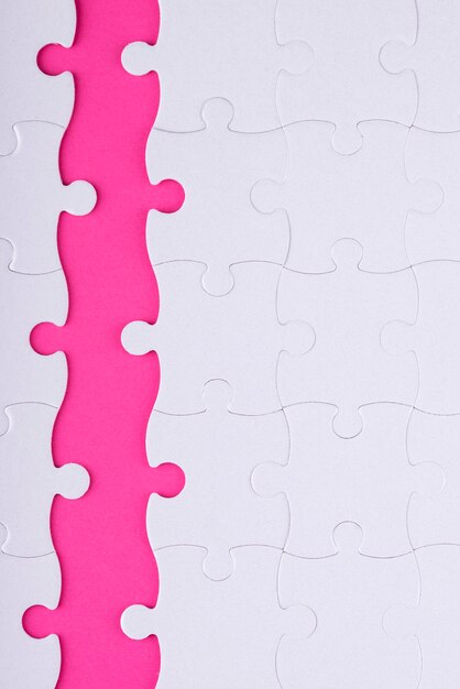 Вид сверху на белые кусочки головоломки и розовый фон