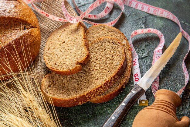 Above view of whole and cut dietary black bread and spikes on brown towel meter on dark colors surface