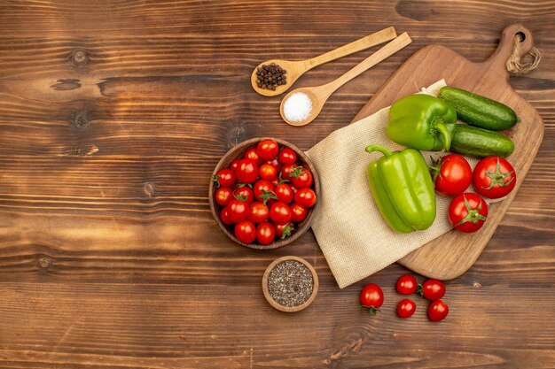 Above view of whole fresh vegetables and spices on brown wooden board with free space