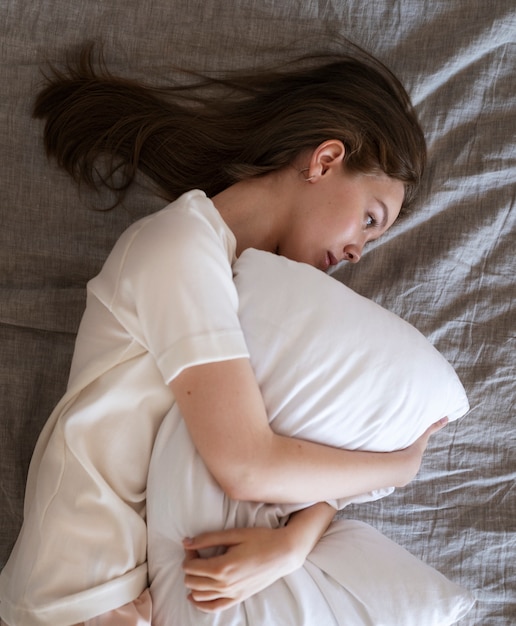 Above view woman laying in bed with pillow