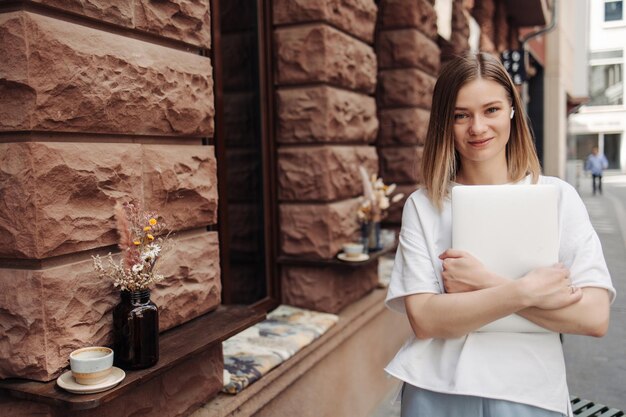 View of woman smiling at camera in withe tshirt with laptop