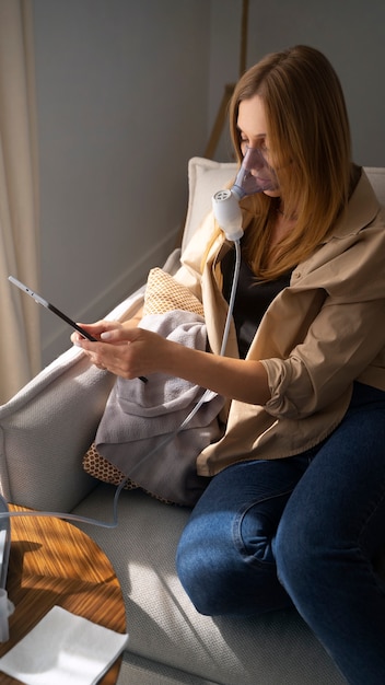 Free photo view of woman using nebulizer at home for respiratory health problems