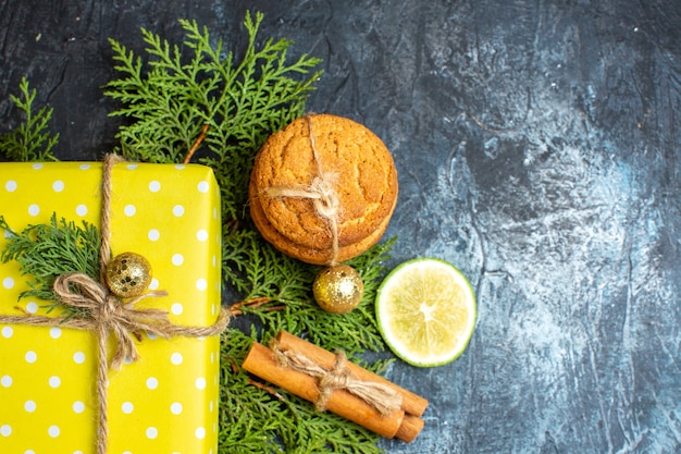 Sopra la vista dello sfondo di natale con bellissime scatole regalo gialle e biscotti impilati limone e cannella lime sul lato destro sul tavolo scuro