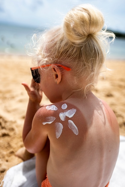 Free photo view of young girl at the beach with lotion on sunburn skin