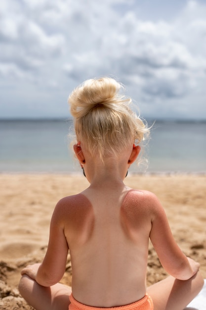 View of young girl with sunburn skin at the beach