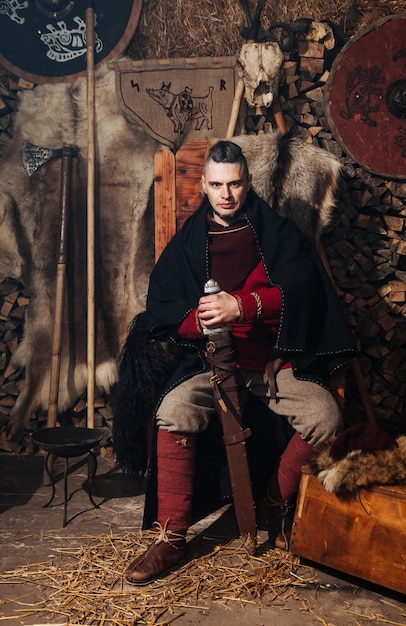 Викинг позирует на фоне древнего интерьера викингов.