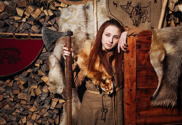 Женщина-викинг позирует на фоне древнего интерьера викингов.