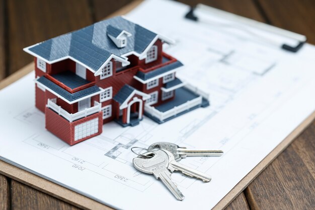 Модель виллы, ключ и рисунок на ретро-столе (концепция продажи недвижимости)