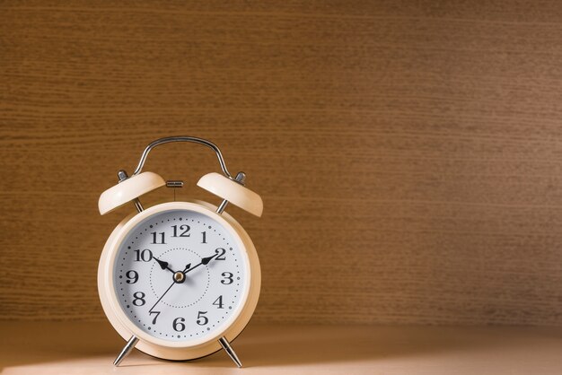 Vintage alarm clock against wooden textured background