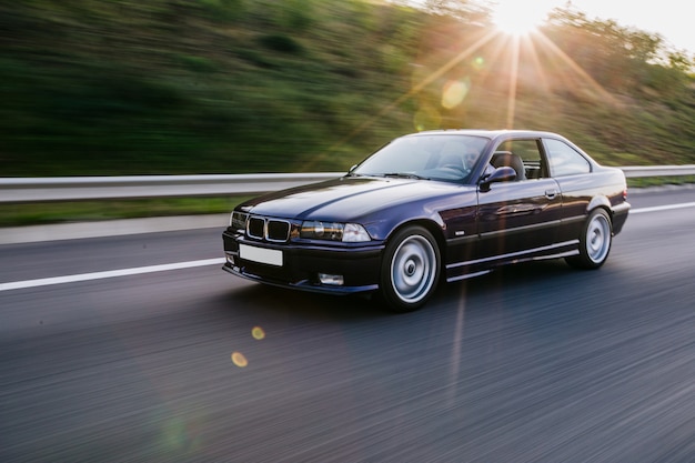 Free photo vintage bordeaux sedan drive under the sunlight.