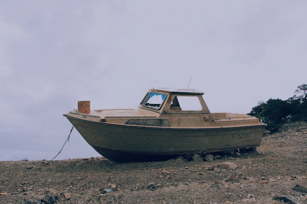 Vintage brown boat on a rocky and sandy surface