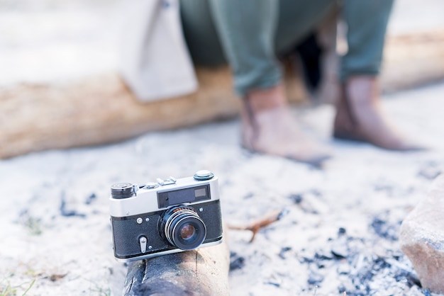 Vintage camera on log with traveler at background