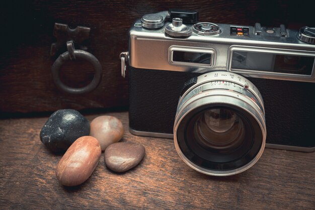 Vintage camera and natural stones on a wooden table near the old chest