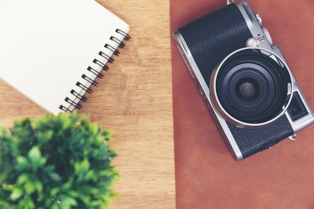 Vintage camera with paper note on wooden table.