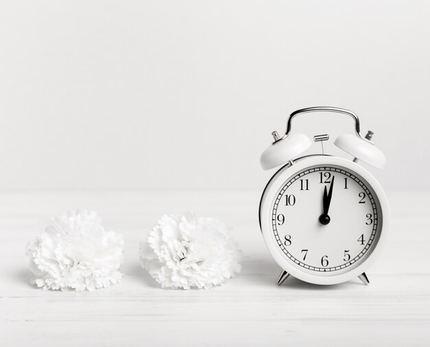 Vintage clock with white flowers beside