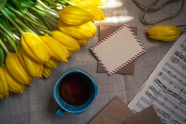 Free photo vintage composition with a cup of tea tulips and notes flat lay