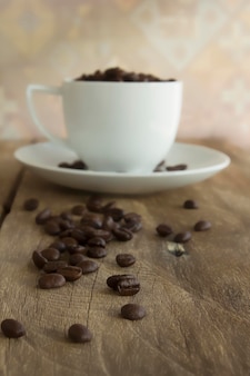 Винтажная чашка жареных кофейных зерен на деревянных фоне