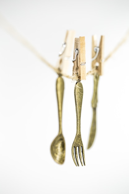 Free photo vintage decorative small cutlery hanging on a rope isolated on white