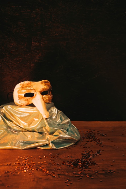 背景に暗いスパンコールが付いているビンテージゴールドカーニバルマスク