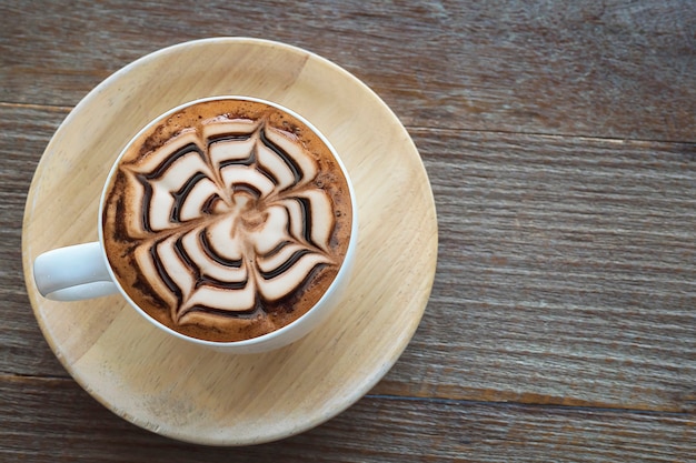 Vintage hot coffee cup with nice Latte art decoration on old wooden texture table