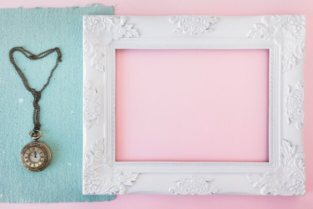 Vintage photo frame near blue paper and old pocket watch 