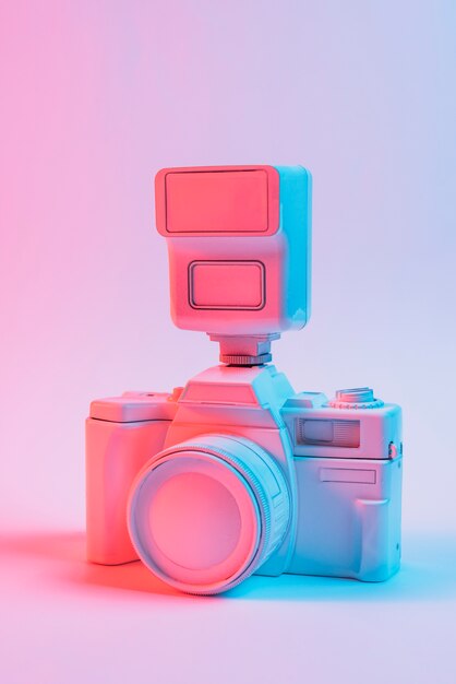 Vintage pink painted camera with lens against pink backdrop