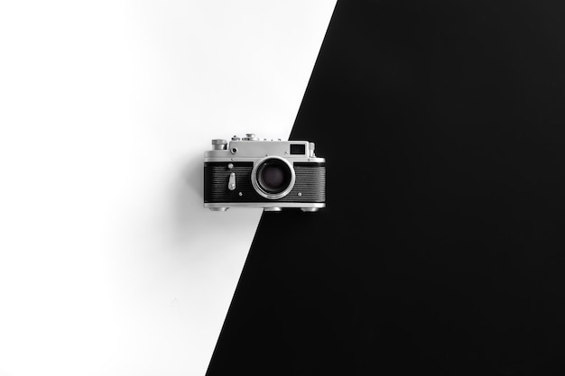Vintage retro camera on black and white background flat lay