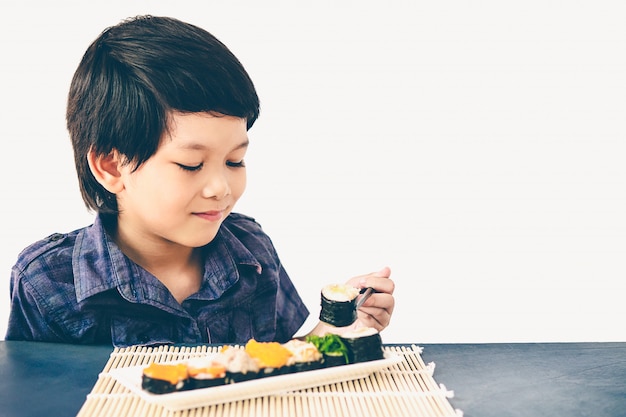 아시아 사랑스러운 소년의 빈티지 스타일 사진은 초밥을 먹고있다