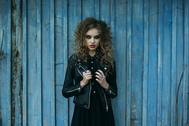 Vintage woman as witch, posing against the backdrop of an abandoned place on the eve of Halloween