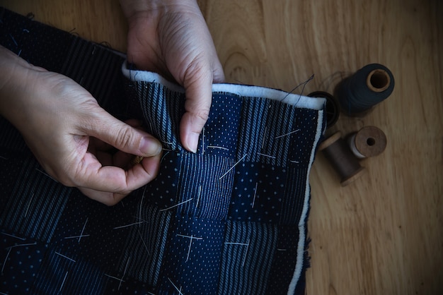 Vintage woman sewing cloth by hand with embroidery set on wooden table - people and handmade diy housework concept