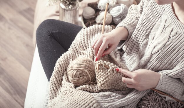 Vintage wooden knitting needles and yarn in woman's hands