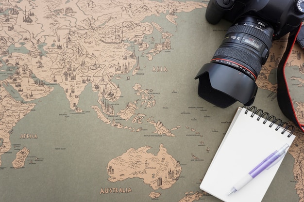 Урожай карта мира фон с ноутбуком, камерой и ручкой