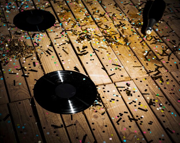 Vinyl records and bottle of drink between confetti