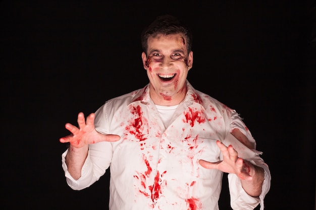 Violent and spooky man with blood on his body over black background.