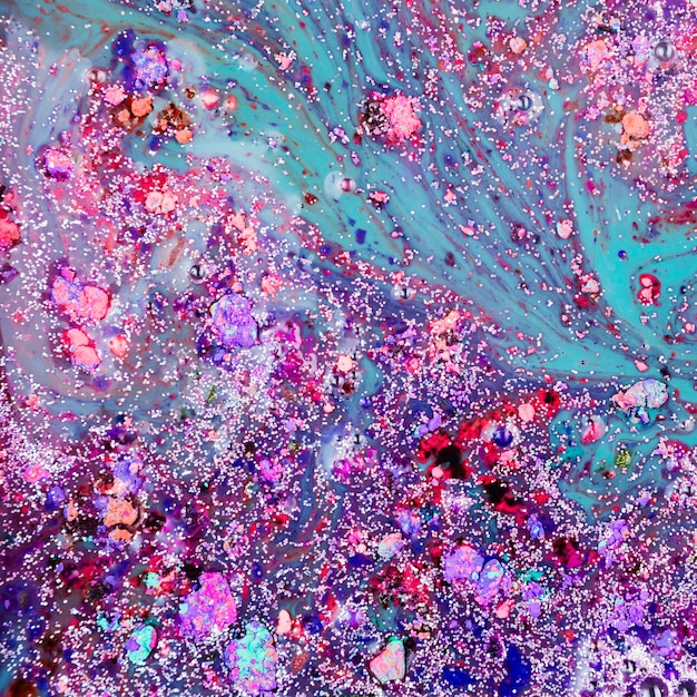 Violet and azure liquid blending with colourful crumbs