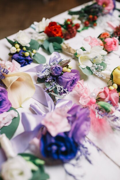 Violet boutonnieres lie among the other on white table