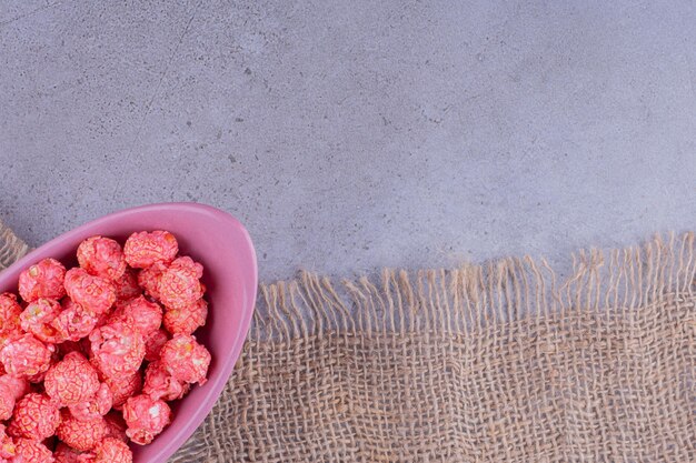 Violet bowl filled with a small serving of flavorous popcorn on marble background. high quality photo