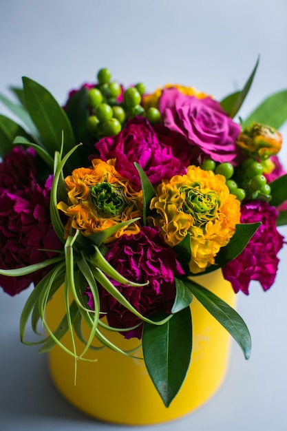 Violet and yellow flowers put in a paper box stand on grey background